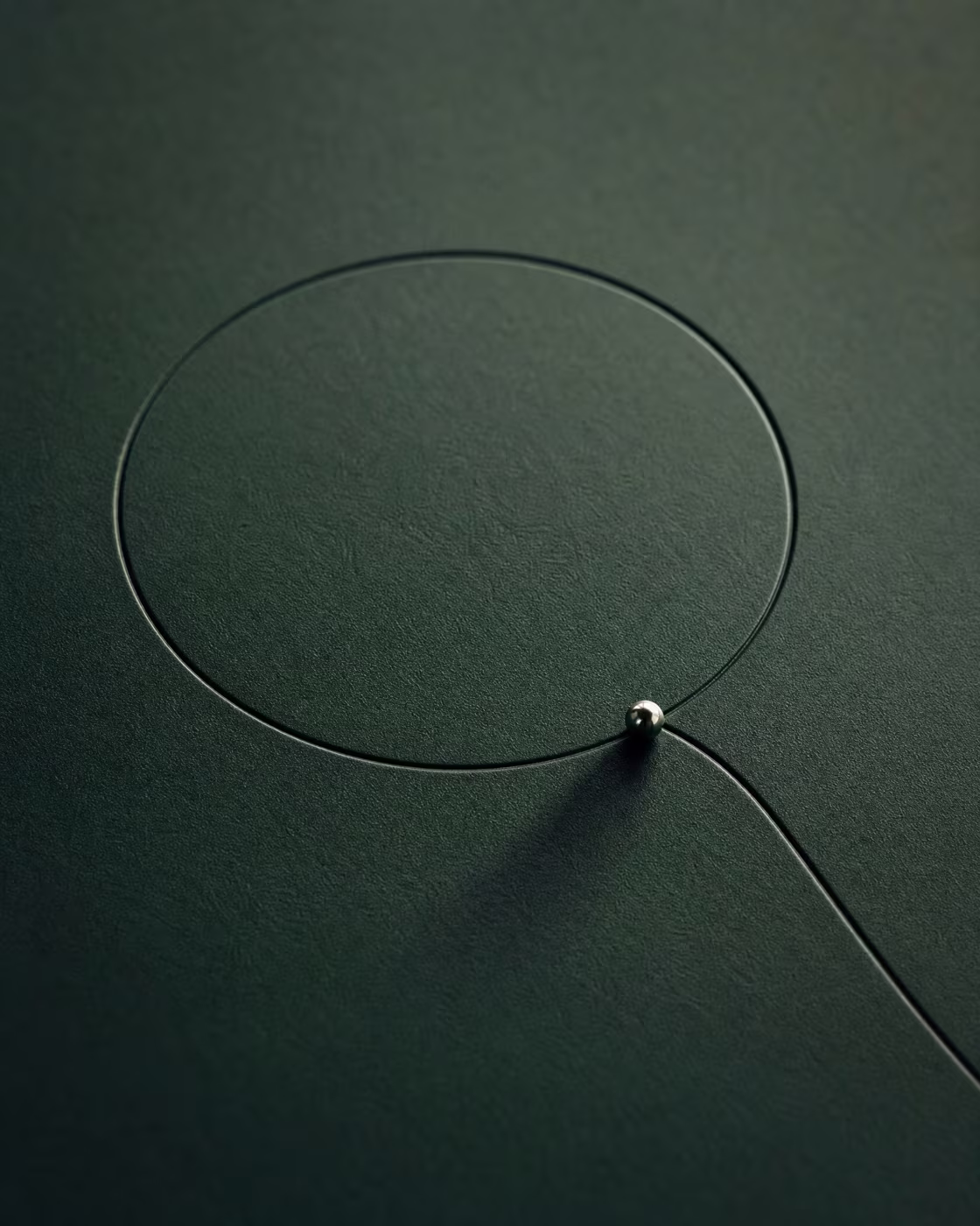A fine wire drawing a circle on a dark green surface
