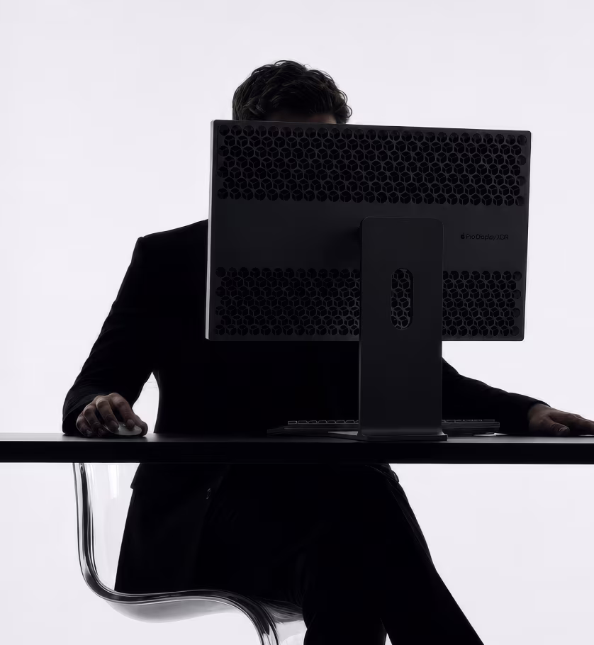 Person at a desk behind a large monitor, silhouette