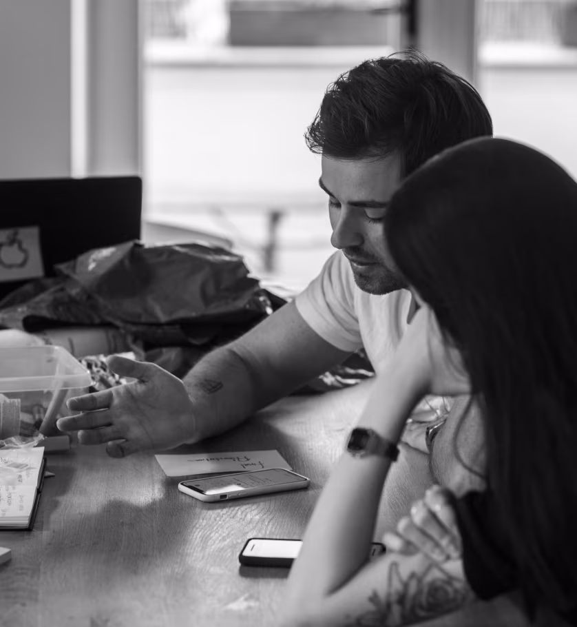 Two people reviewing work together at a table, black and white