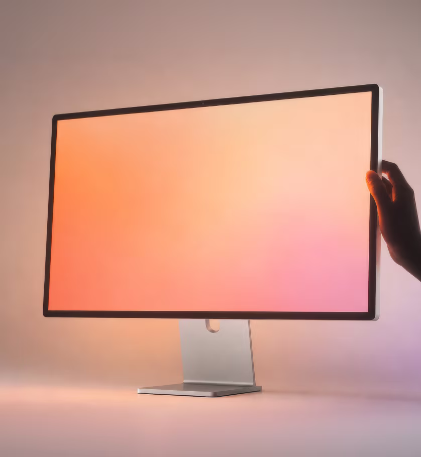 Hand steadying a desktop display with a warm gradient screen