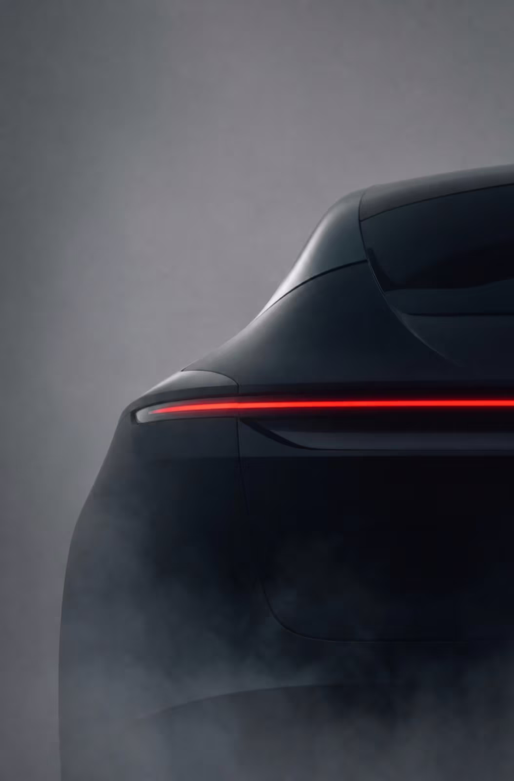 Rear of a dark car with a thin red light bar in fog