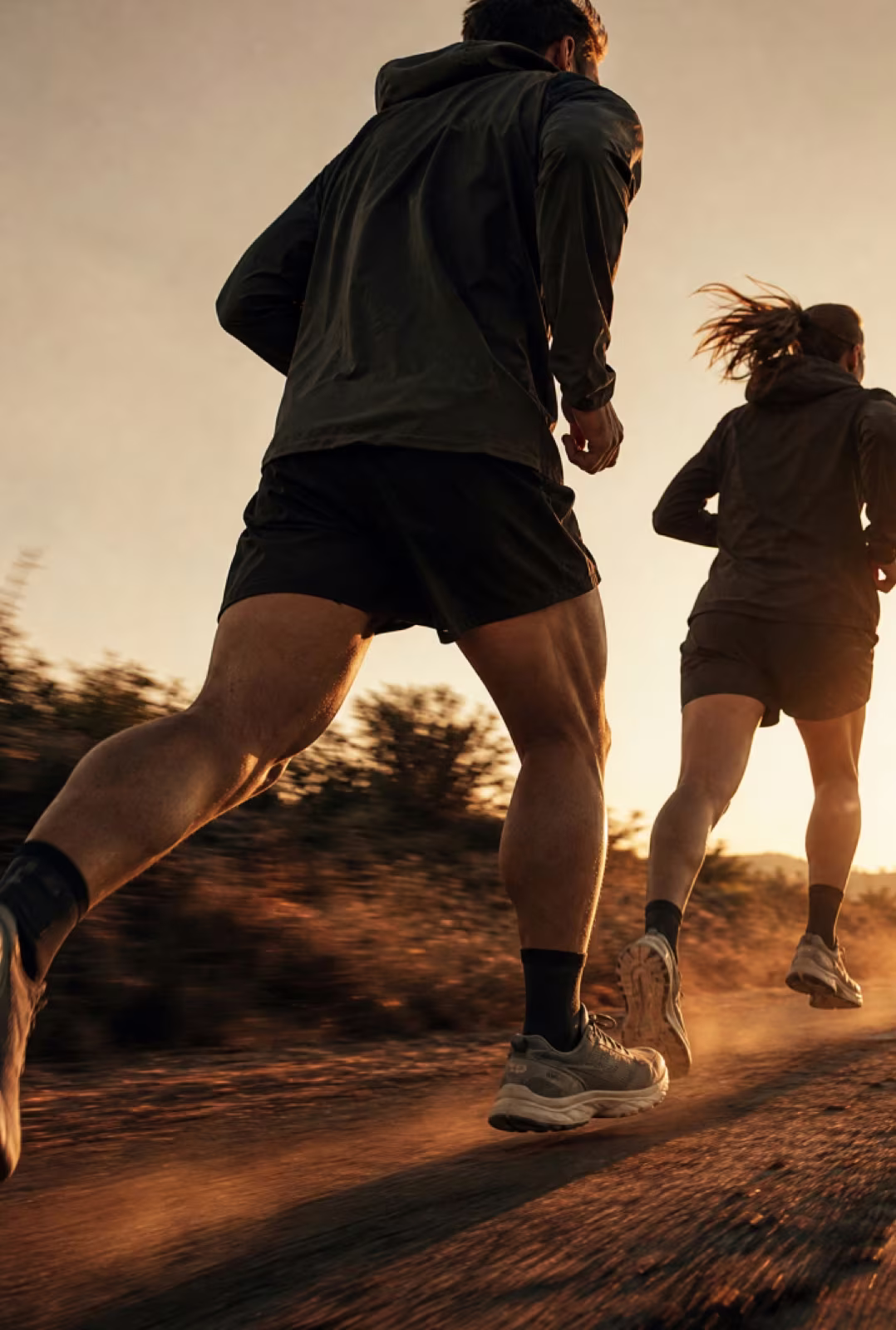 Two runners on a dusty trail at sunset